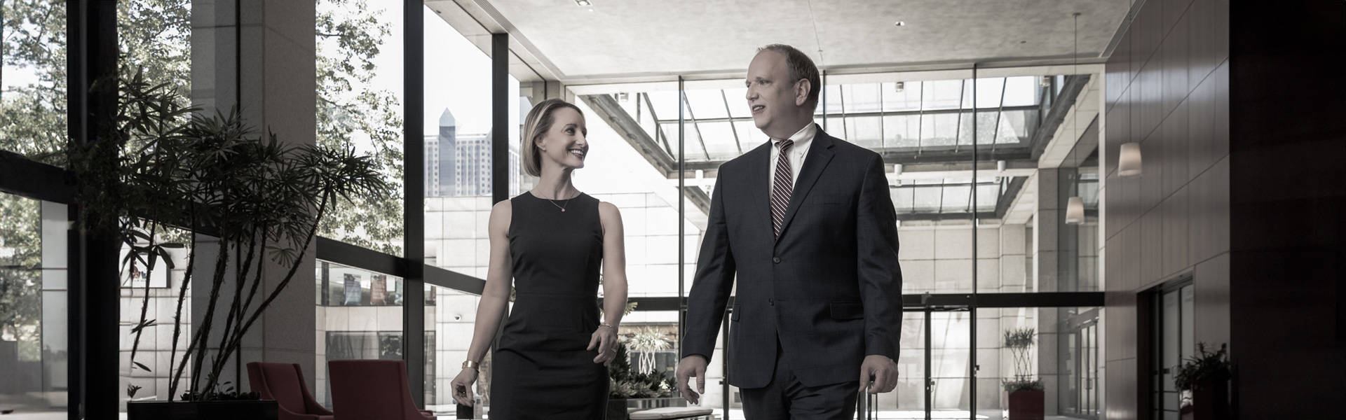 David Ahlheim and Rebecca Cary talk while walking through a glass-walled building