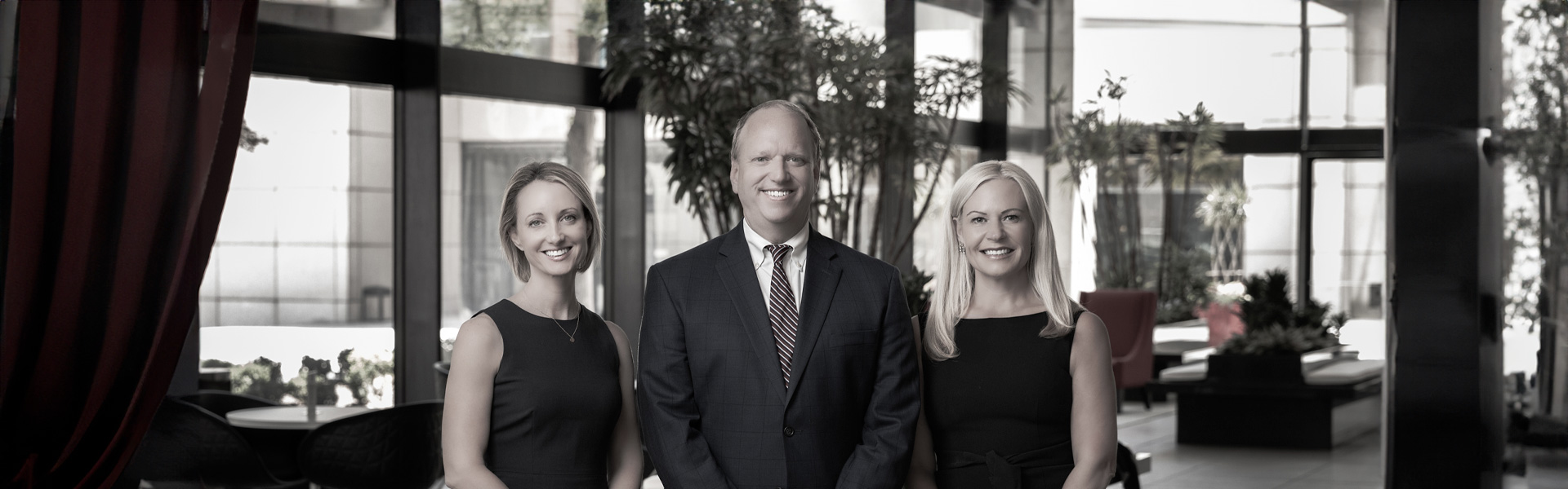 Rebecca Cary, David Ahlheim, and Yvette Boutaugh stand together smiling in an office building lobby